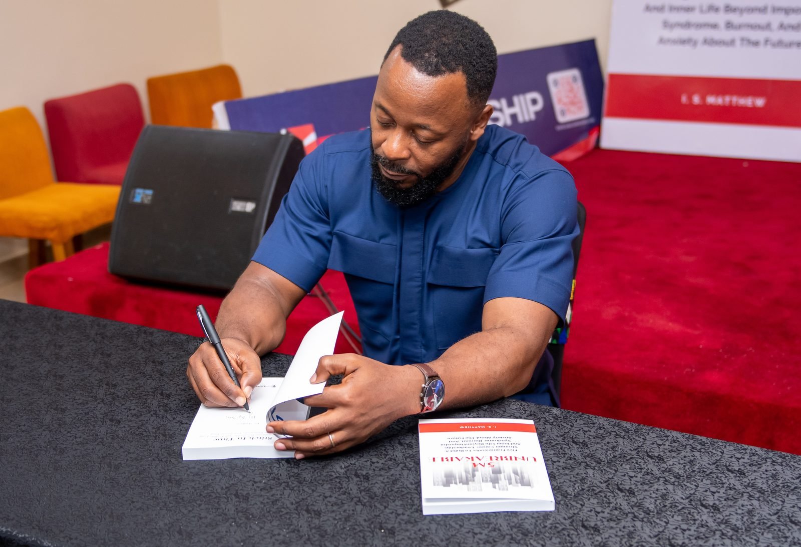 I. S. Matthew signing a copy of a book at the launch
